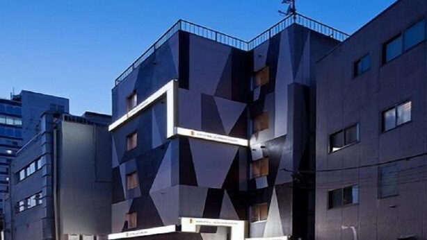 Ein modernes Gebäude mit einer geometrischen Fassade, mehreren Balkonen und einem Flachdach.