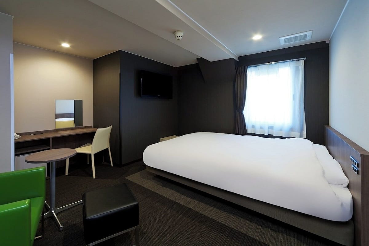 Une chambre d’hôtel comprenant un lit, un bureau, une chaise, une petite table et un téléviseur.
