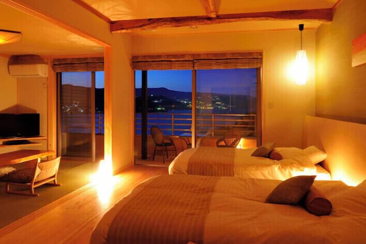 A hotel room with a balcony, a bed, a TV, and a chair.
