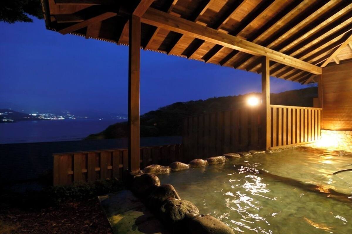A wooden structure with a stone wall and a pool with rocks.
