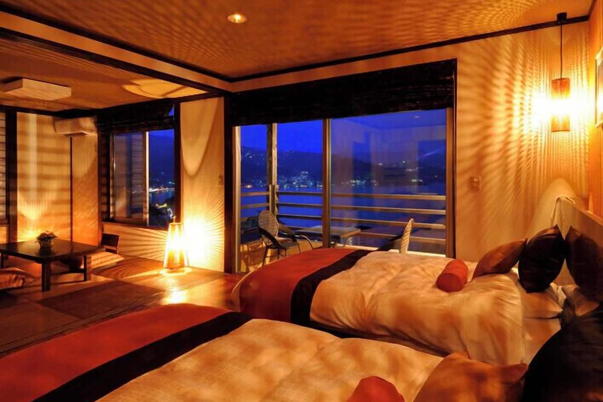 A hotel room with a large window, a bed, a table, and a chair.