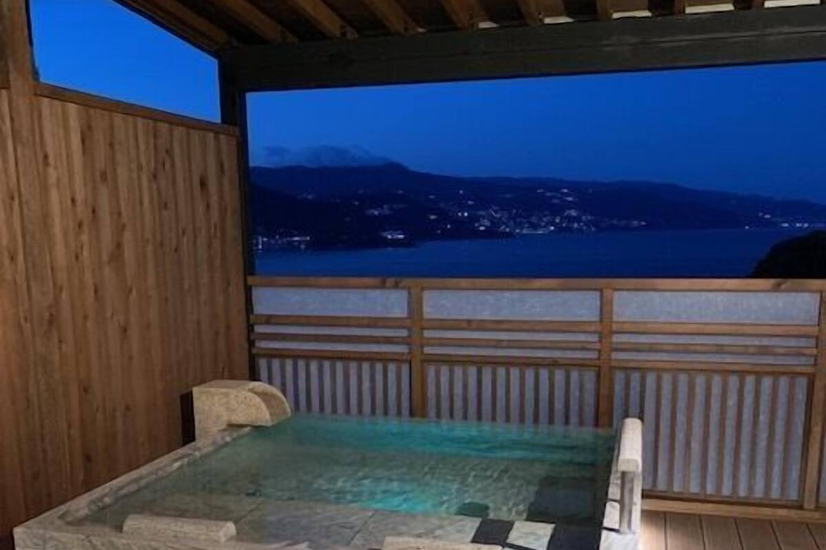 A wooden deck with a stone bench and a view of a body of water at dusk.