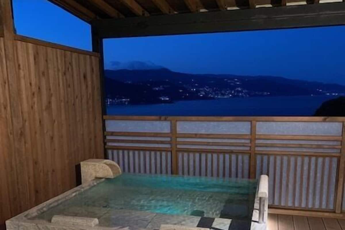 A wooden deck with a stone bench and a view of a body of water at dusk.