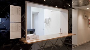 A reception desk with a nameplate labeled "FRONT", a whiteboard with text, and a phone. - Shin-Okubo International Hotel (Tokyo)