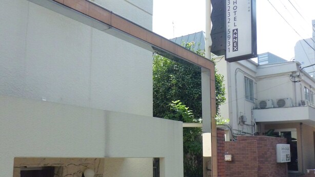 A modern hotel with a stone facade, a visible entrance, and a signboard indicating the name and address. - Shin-Okubo International Hotel (Tokyo)