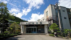 A building with a sign that reads 'Hotel' and a parking lot in front. - Ryokan Aizu Yunokami Onsen Hotel Osakaya (MINAMIAIZU GUN SHIMOGO MA)