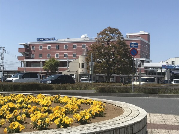 Un edificio de varios pisos, un estacionamiento y un parterre con flores amarillas.