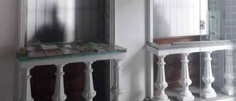 Una habitación con dos ventanas arqueadas, un televisor montado en la pared y una mesita con base estampada.