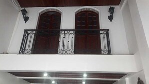 Un balcón con barandillas metálicas ornamentadas y dos puertas de madera.