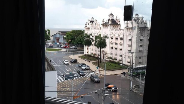 Vista de una calle urbana con un edificio grande y ornamentado al fondo.