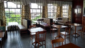 Un restaurante con techos altos, ventanas amplias y una variedad de asientos, incluyendo mesas y bancos.