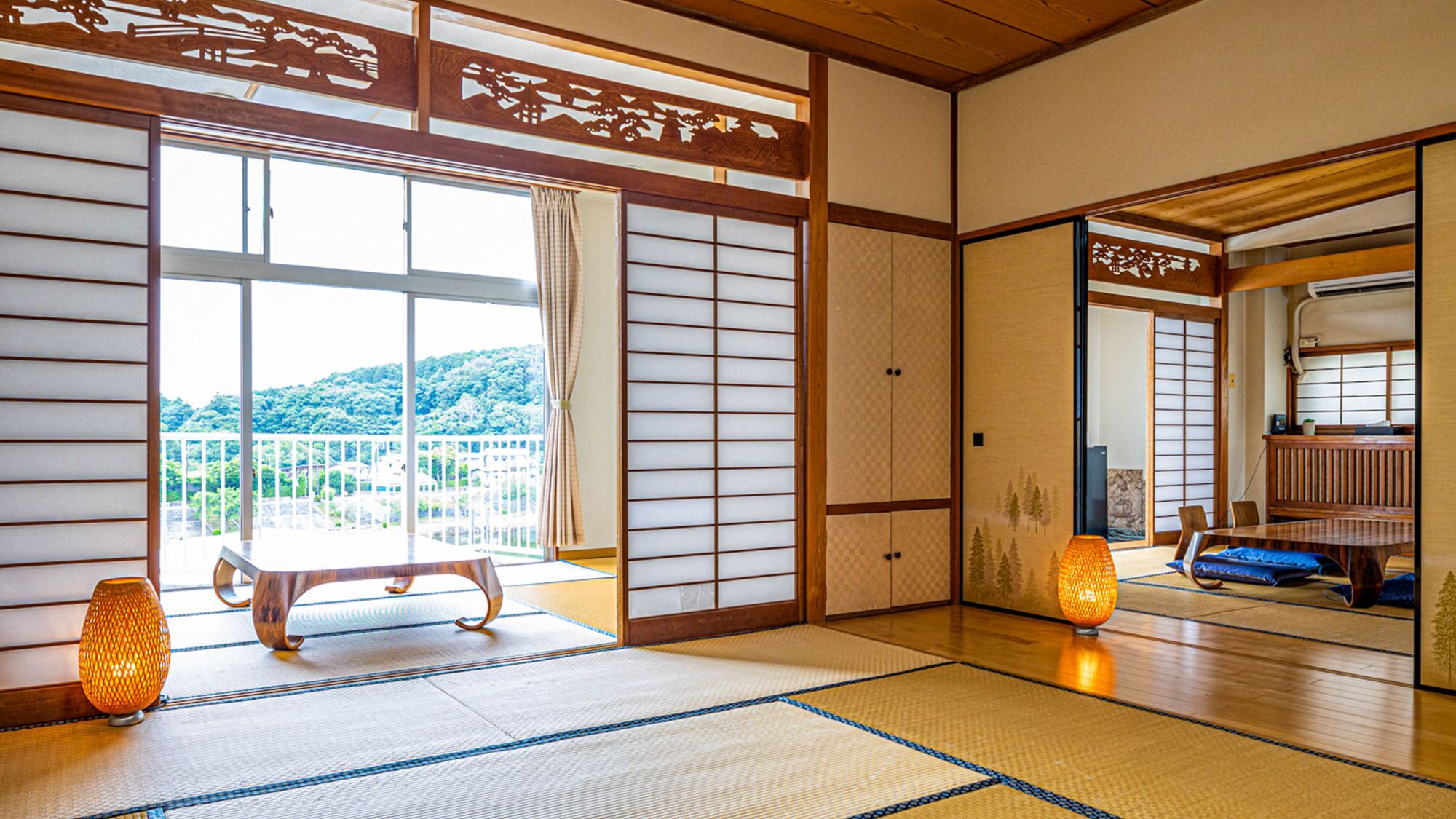 A traditional Japanese room with tatami flooring, sliding doors, and a view of a mountainous landscape.