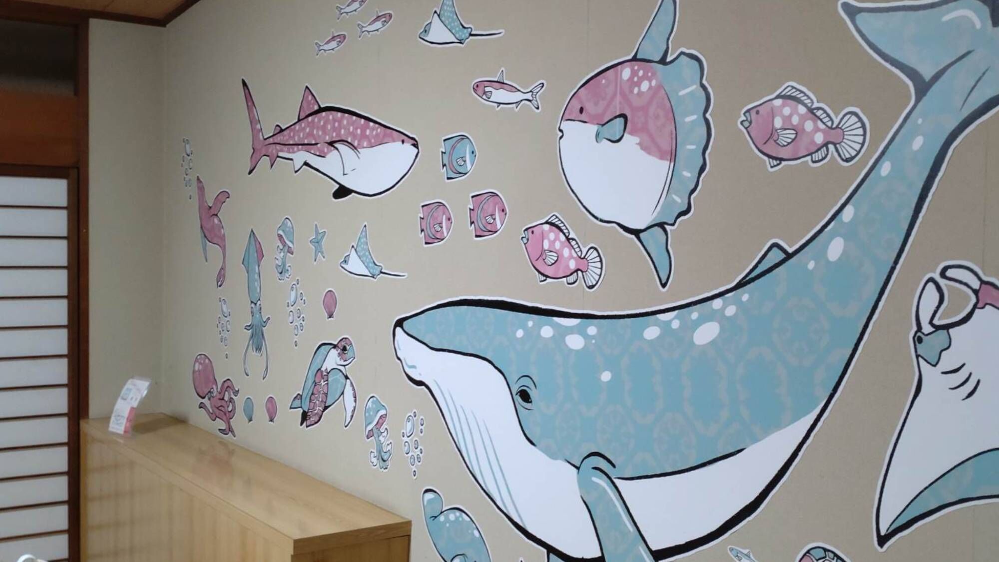 A wall with a marine-themed mural including various fish and a whale.