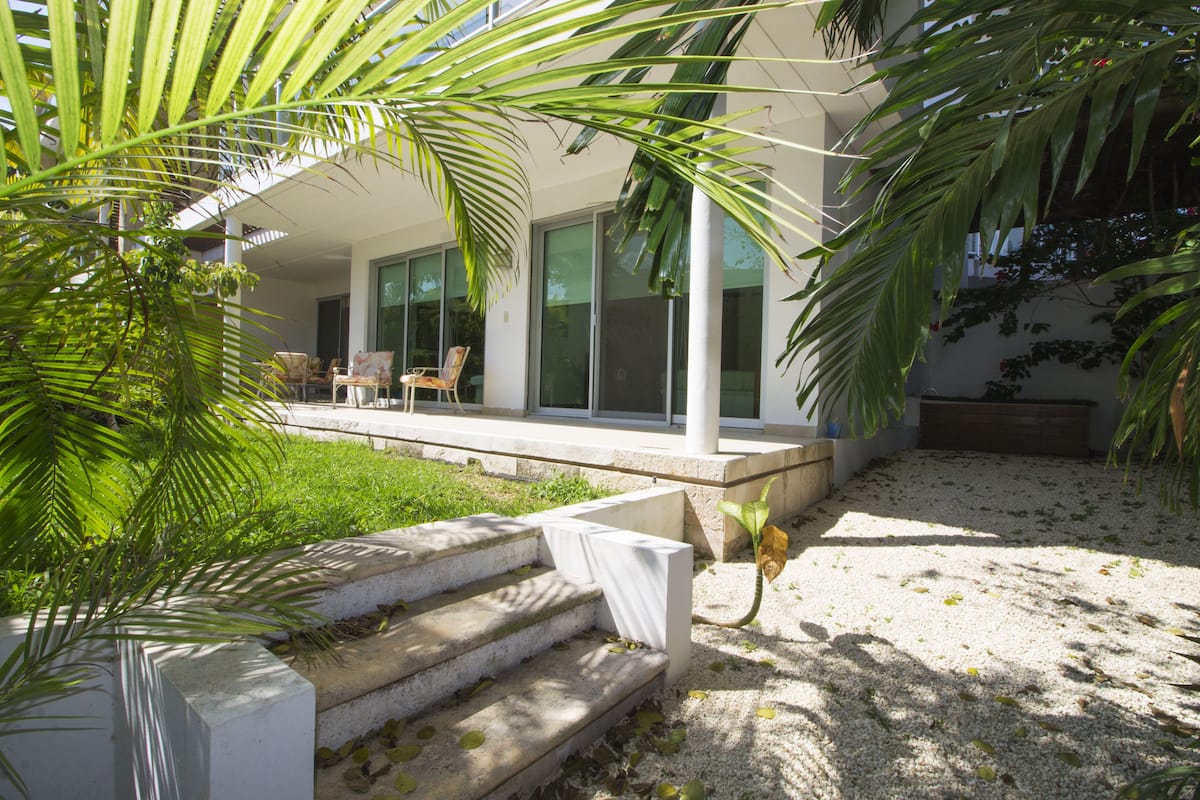 A modern outdoor area with a concrete staircase leading to a covered seating area with chairs.