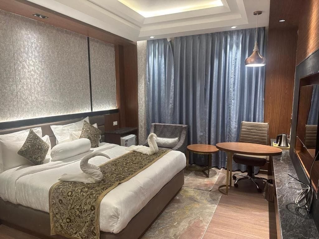 A hotel room with a large bed, a small table, a chair, and a desk with a chair.