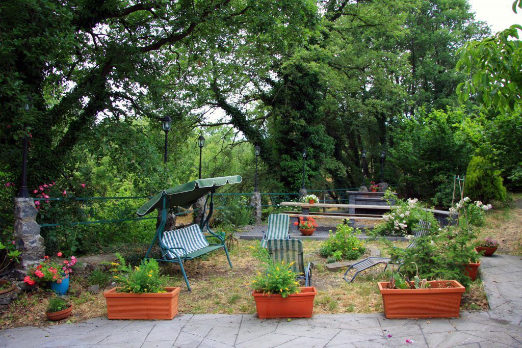 A garden patio with outdoor seating, potted plants, and a stone wall.