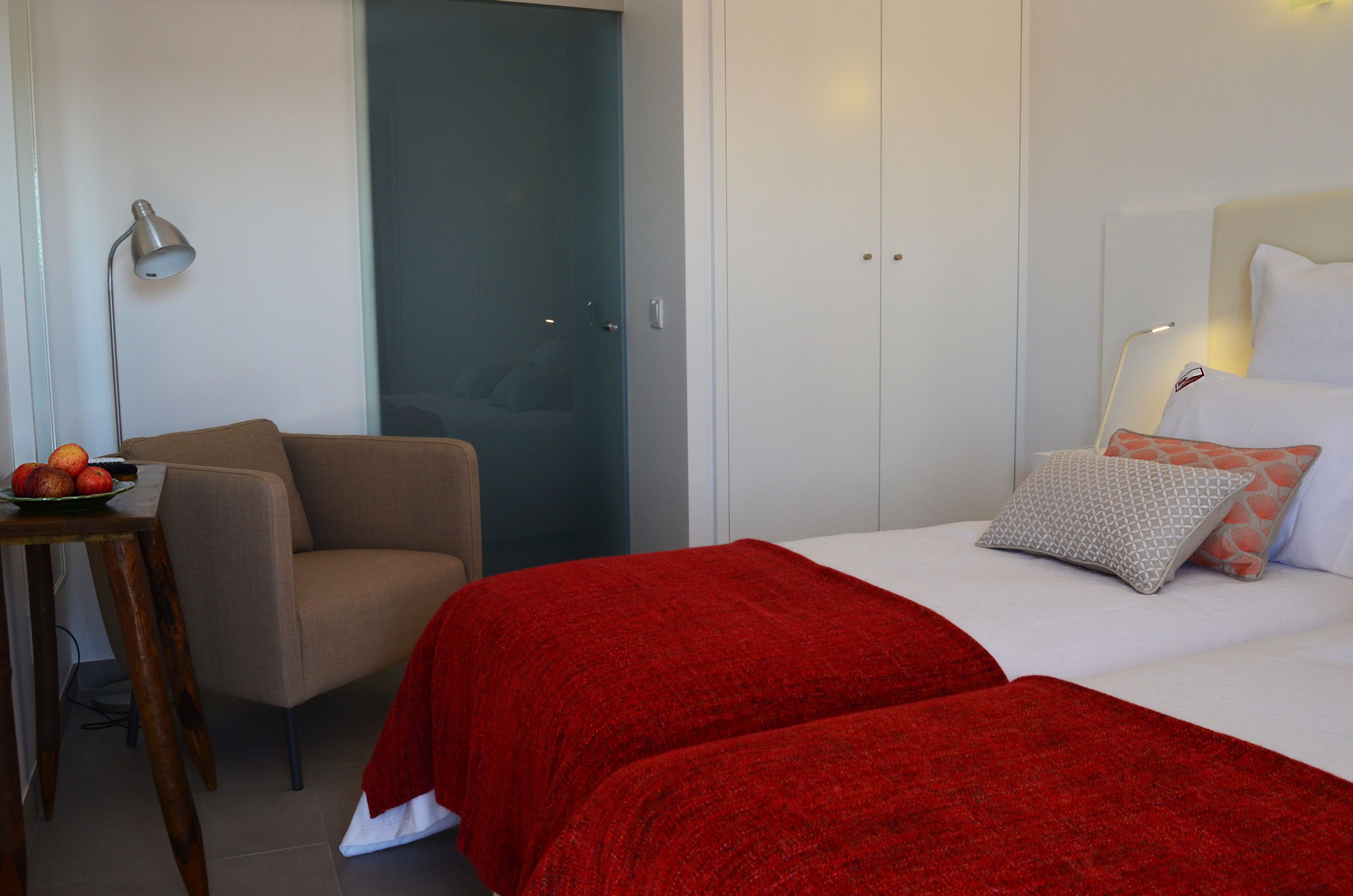 Un dormitorio con una cama, una silla, una mesa con fruta y un armario.