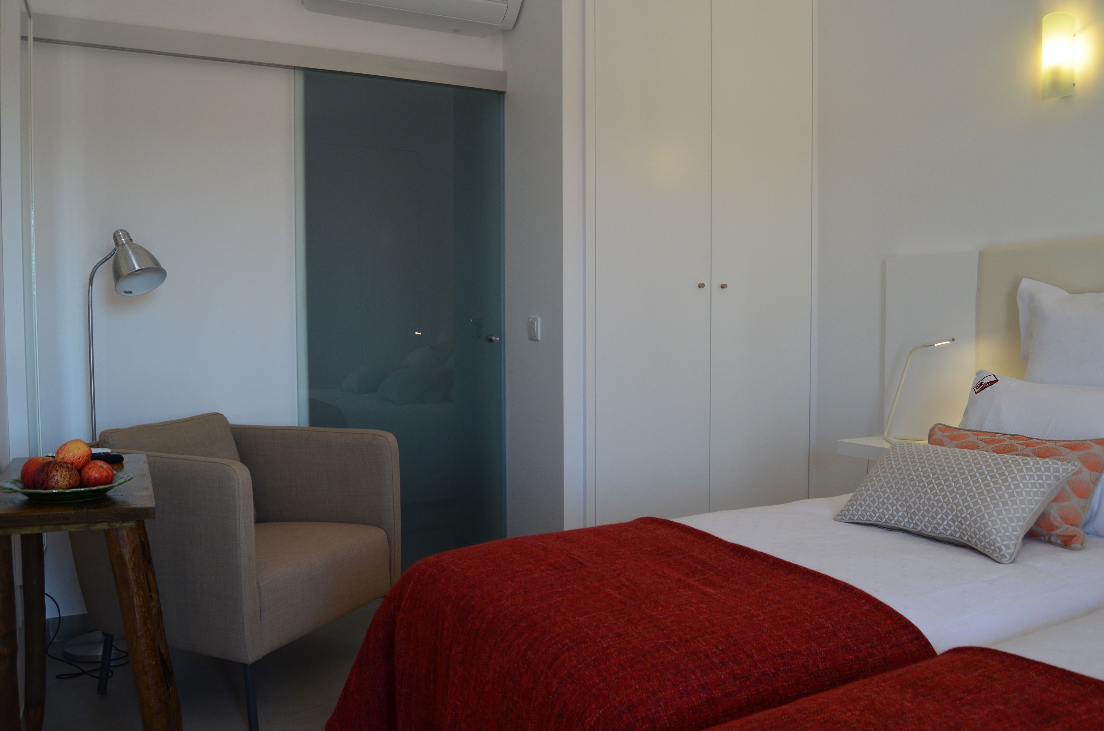 Una habitación de hotel con una cama, una silla, una mesa con fruta y un armario.