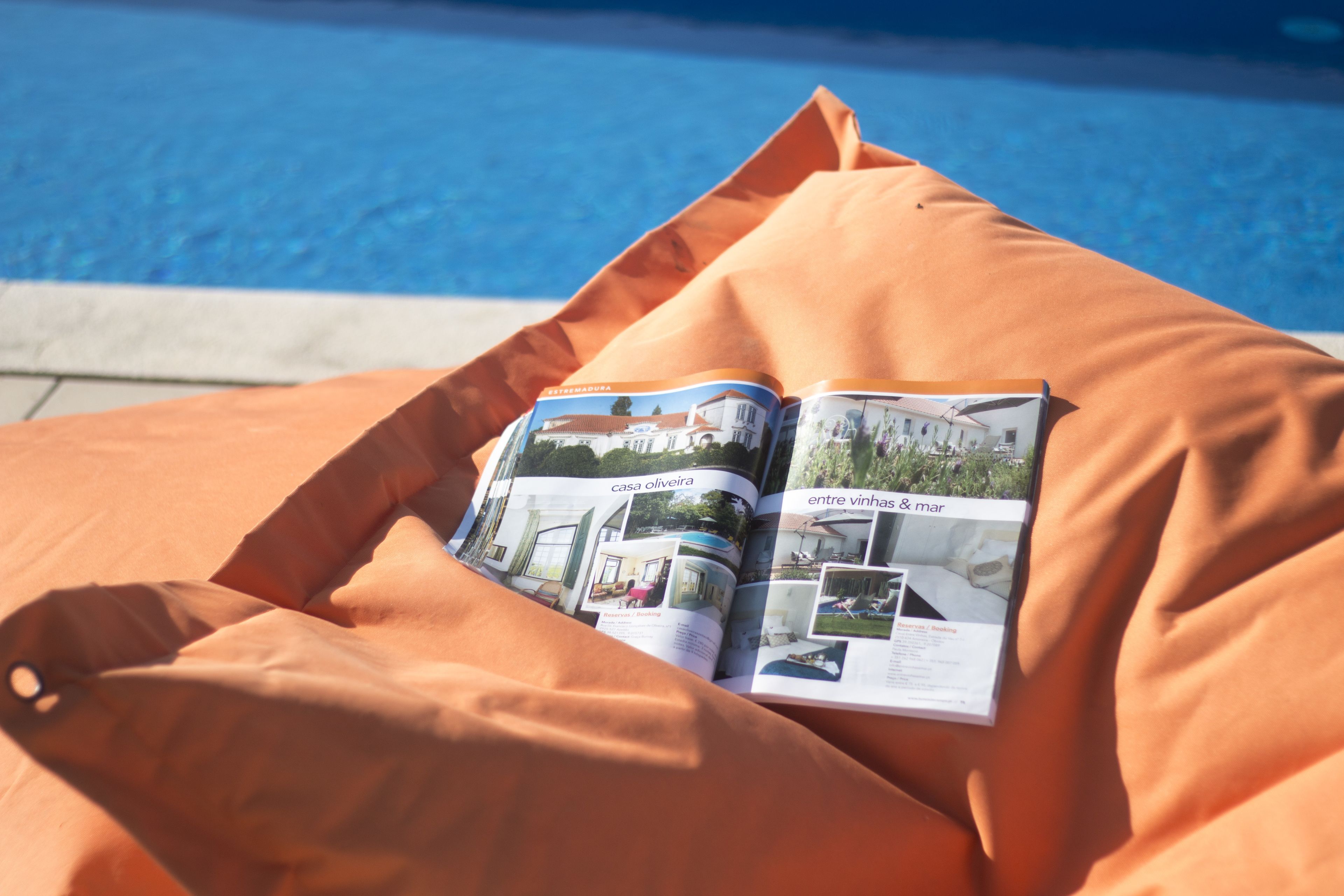 Una revista sobre una silla de playa junto a una piscina.