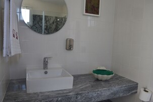 A bathroom with a white sink, a mirror, a soap dispenser, and a decorative bowl on the countertop.