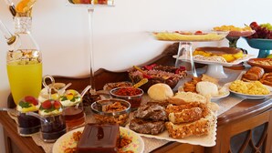 Un bufé de desayuno con diversos platos, incluyendo bollería, frutas y bebidas.