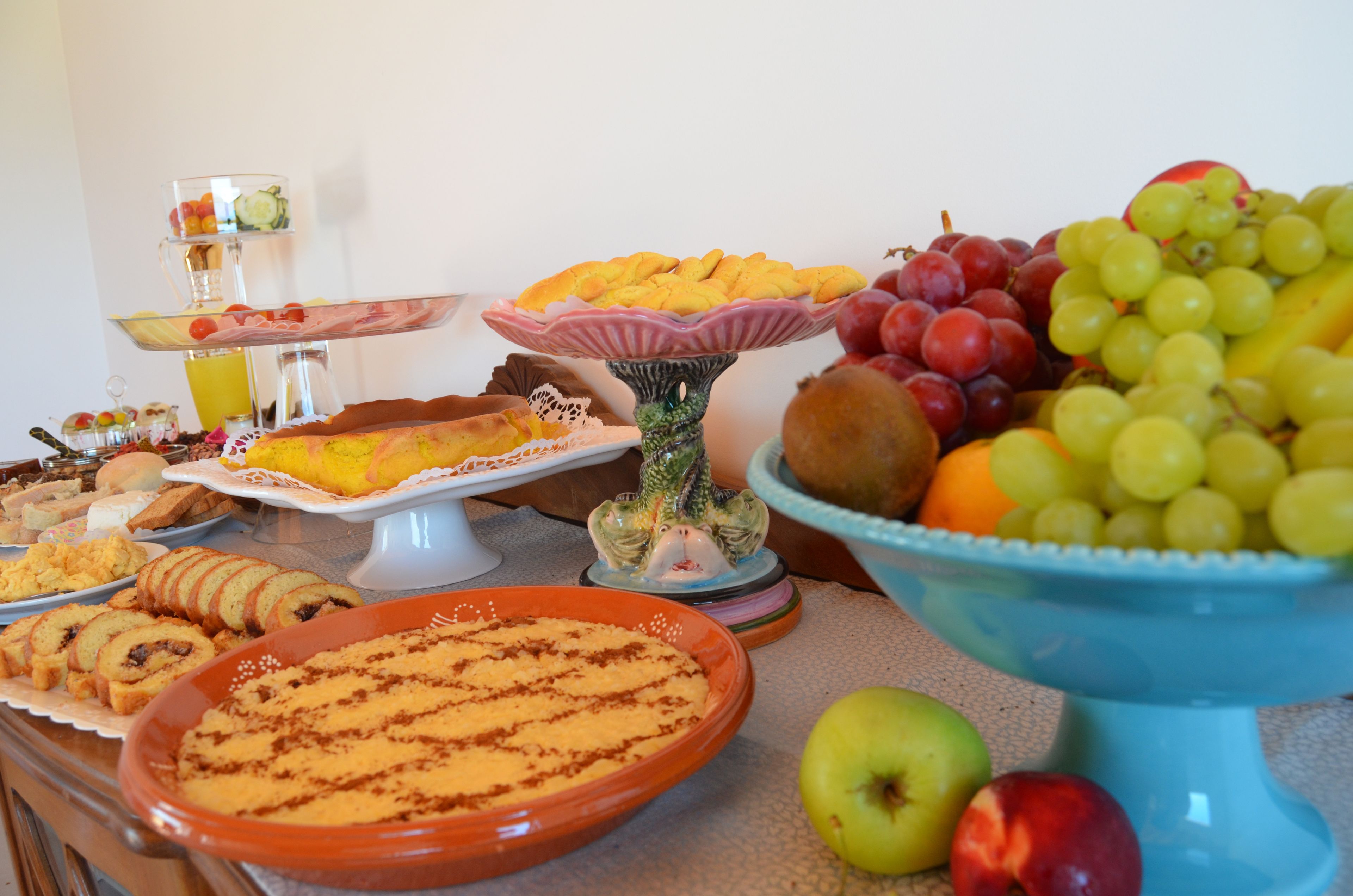 Une table de buffet proposant une variété d’aliments, notamment des fruits, des pâtisseries et une grande tarte.