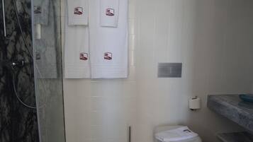 A bathroom with a shower, toilet, and marble-tiled walls.