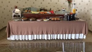 Una mesa con manteles marrones presenta una variedad de alimentos y bebidas en estilo bufé.
