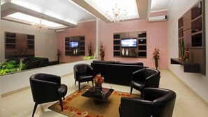 Una sala de estar moderna con un sofá, sillones, una mesa de centro y un televisor.