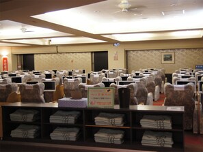 A hotel room with multiple beds, a reception desk, and a sign indicating a 9:27 check-in time.