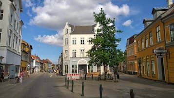 A street view with a white building with a grey roof, a tree in the center, and a sign that reads "Skiolab".