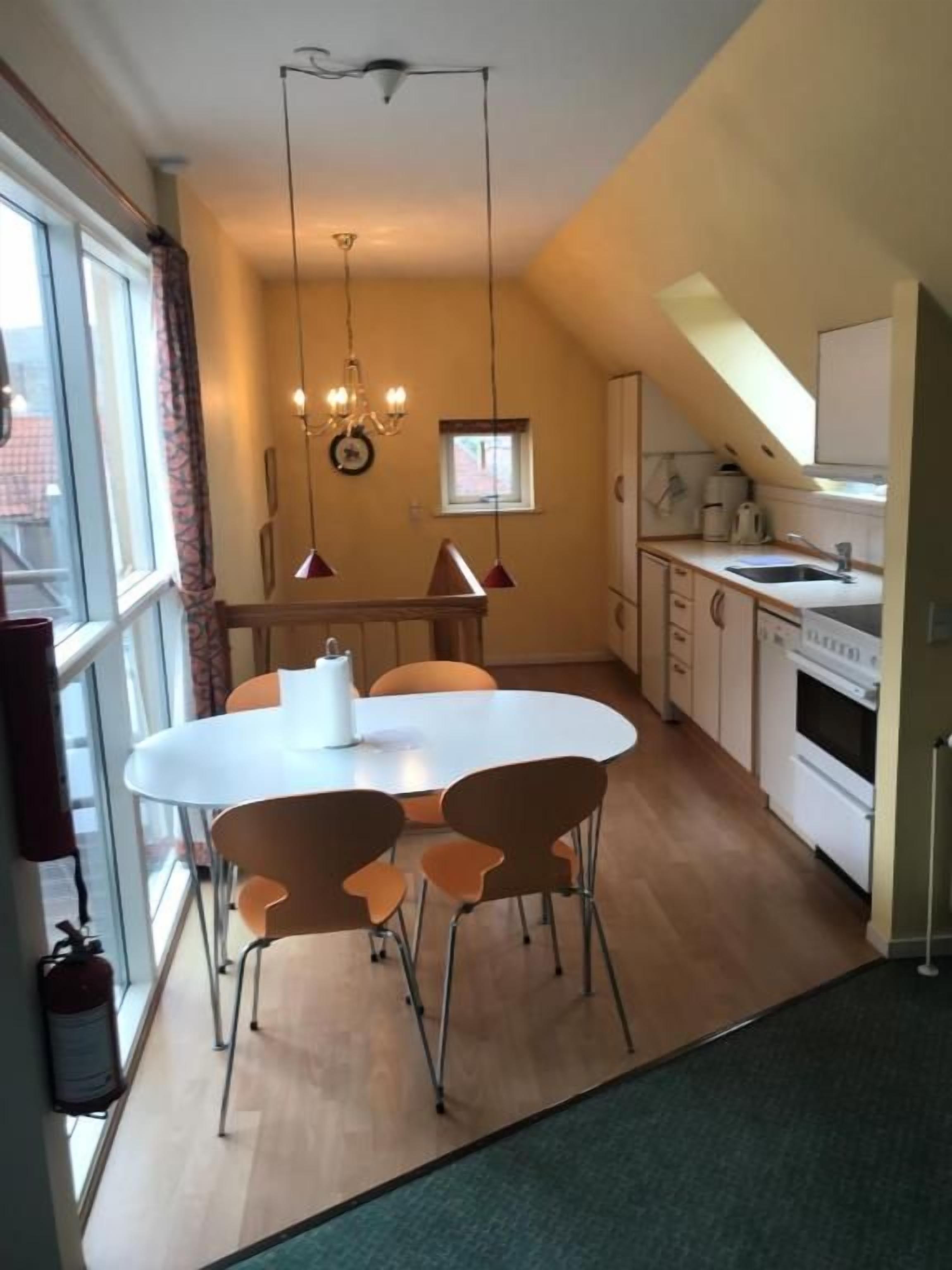 A compact kitchen with a dining area, a window, and a built-in oven.