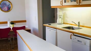 Una cocina con armarios blancos, un lavavajillas Bosch y una cafetera.