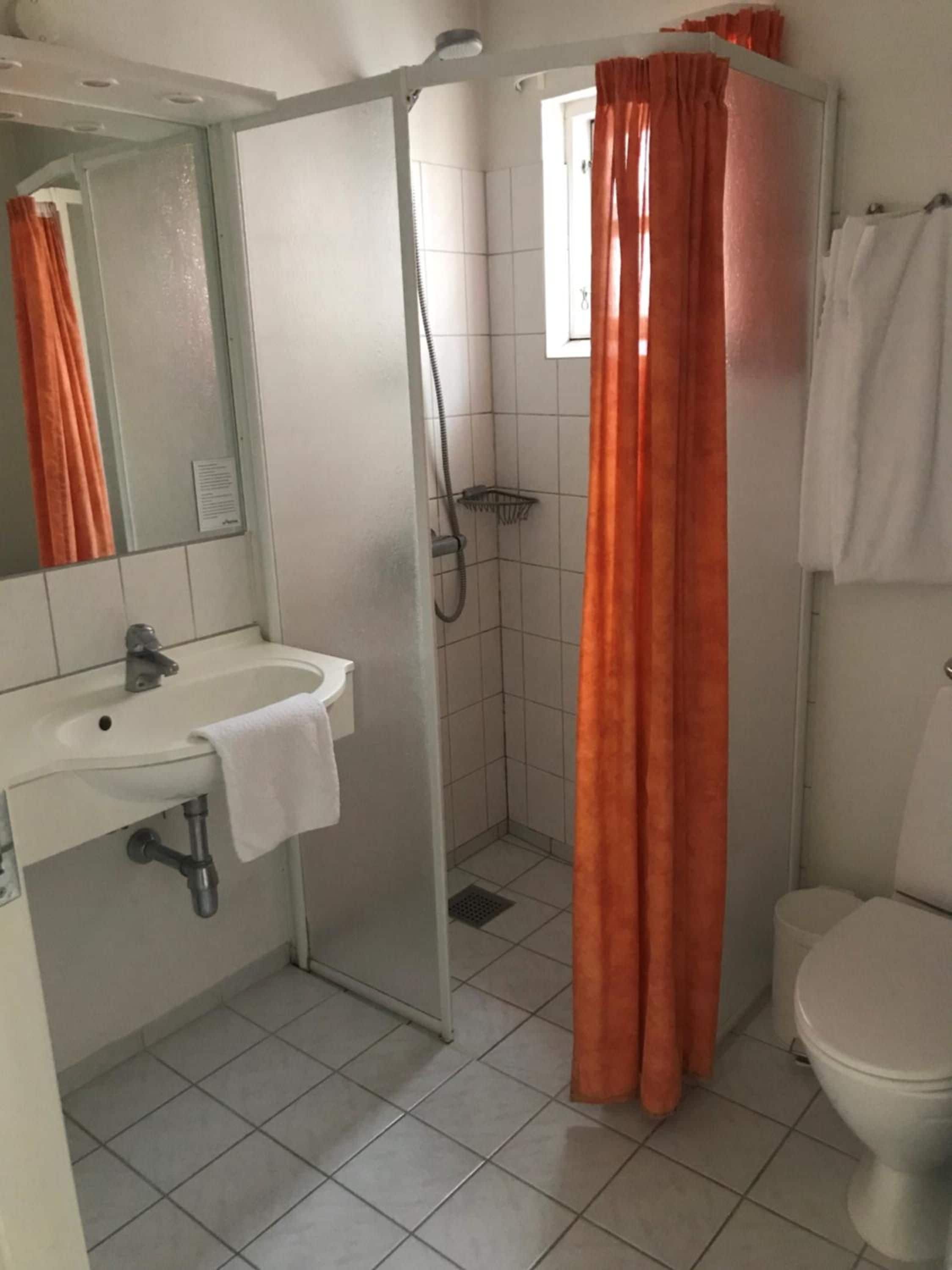 A bathroom with a white sink, a shower with a glass door, and a toilet.