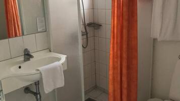 A bathroom with a white sink, a shower with a glass door, and a toilet.