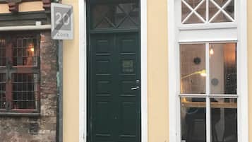 En bygning med en grøn dør og et vindue med hvid ramme. Et skilt angiver en 20-zone.