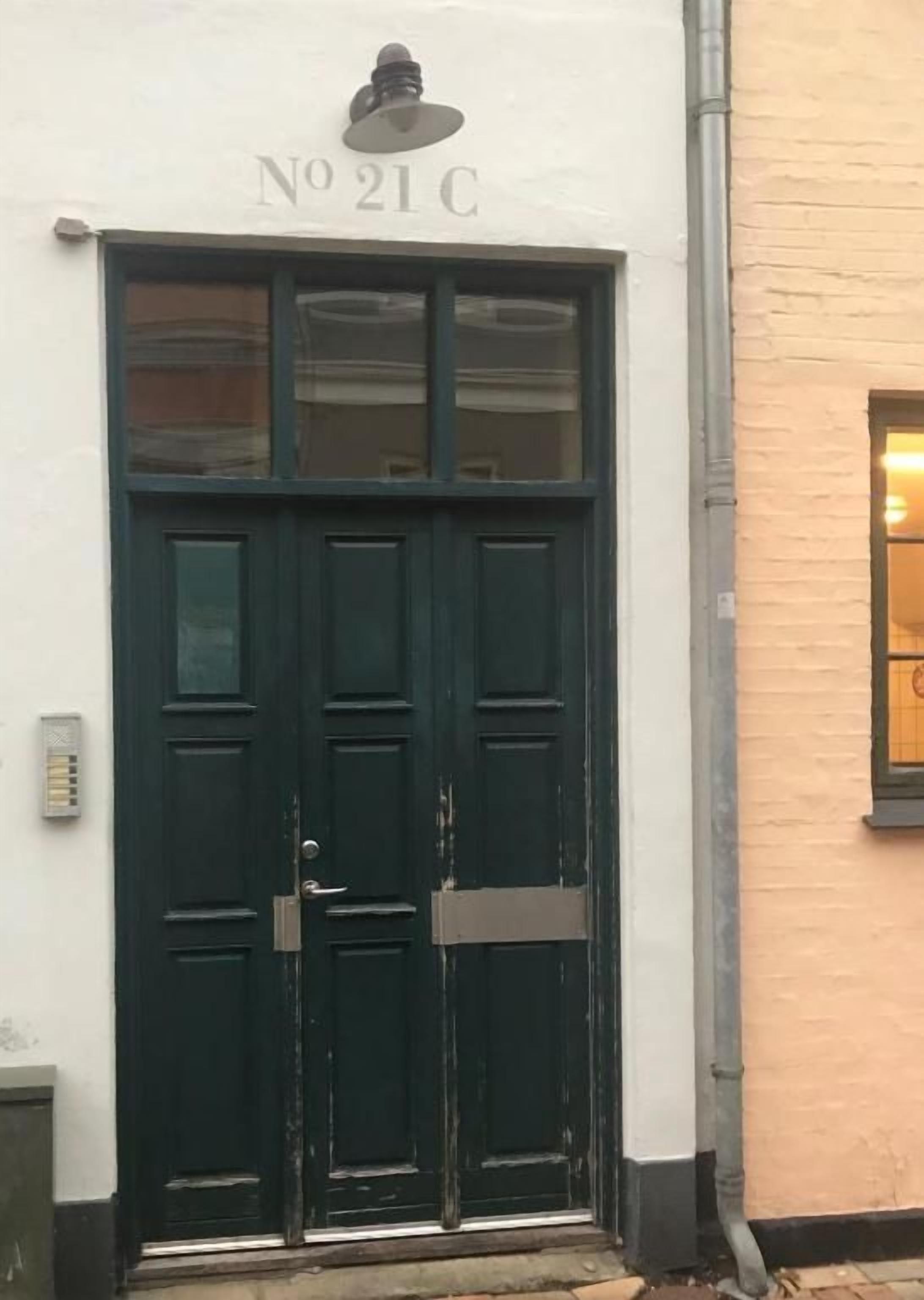 A dark green double door with a sign above it reading 'No 21 C'.
