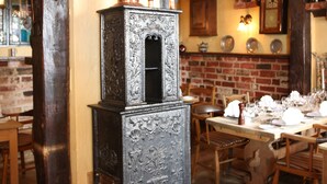 A traditional kitchen with a large stove, wooden beams, and a brick wall. - City Hotel Nattergalen Apartments (Odense)