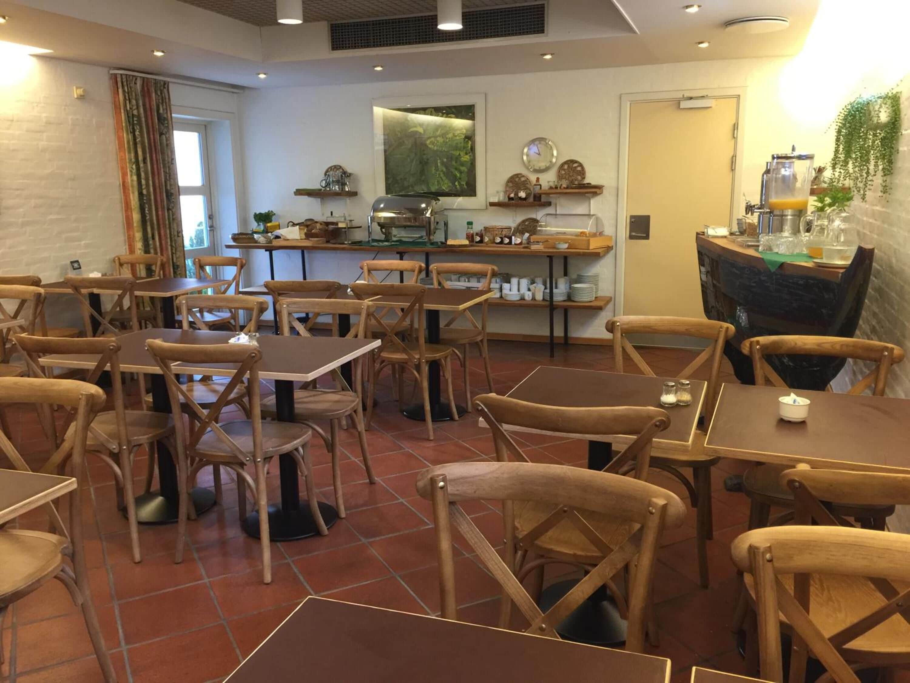 Ein Restaurant mit Holztischen und -stühlen, einer Bar und einer Küche im Hintergrund.