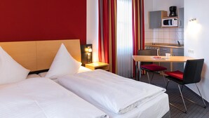 Habitación de hotel con cama, escritorio, silla, microondas y cafetera.