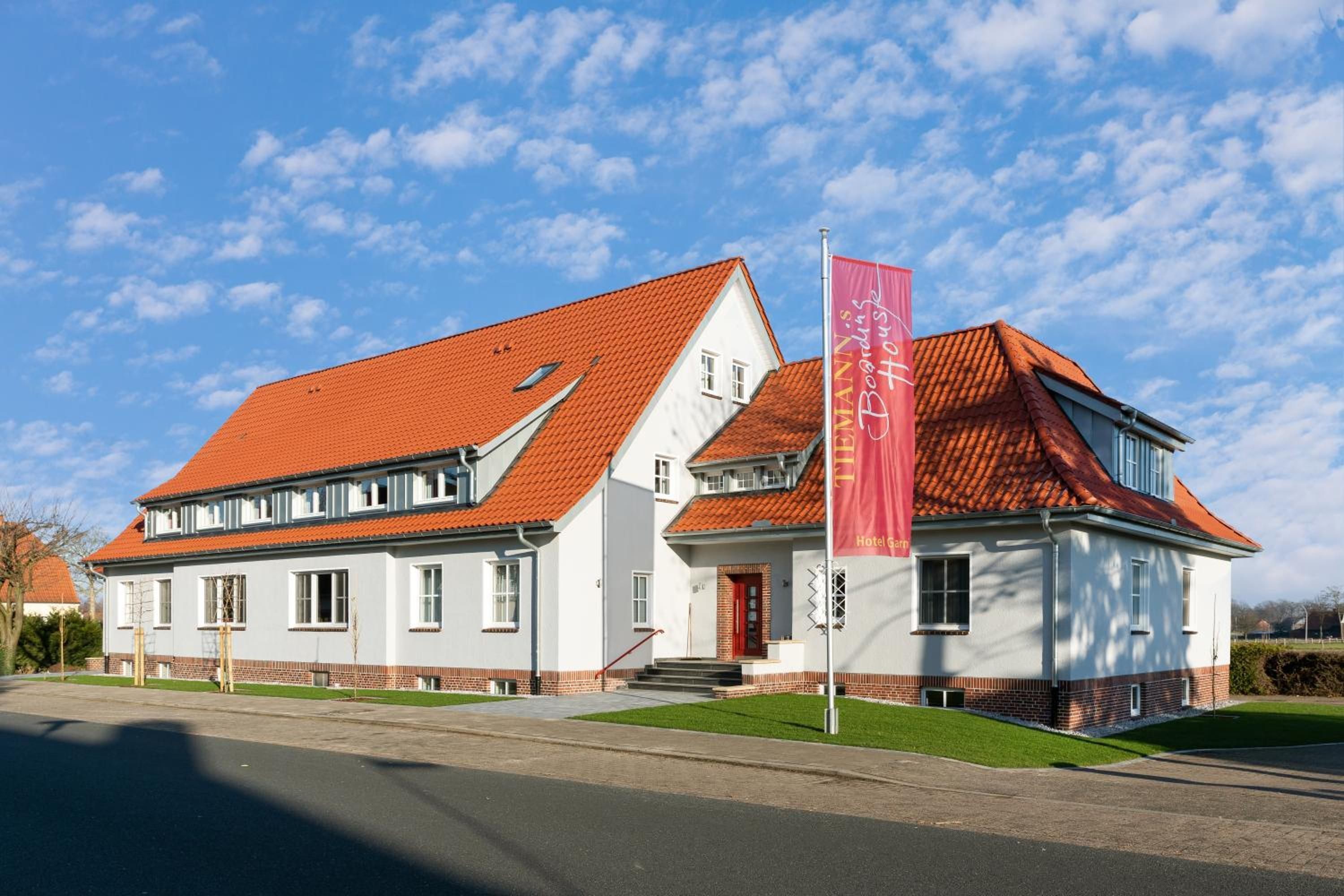 A two-story building with a red-tiled roof, a prominent red banner, and a brick facade.