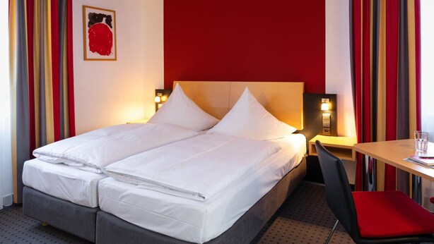 Una habitación de hotel con una cama, un escritorio y una silla.