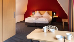 Una habitación de hotel con una cama, mesitas de noche, un escritorio y una silla.