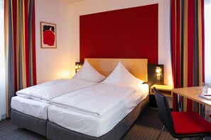 A hotel room with a bed, a desk, and a chair. - Tiemanns Boardinghouse (Lemfoerde)