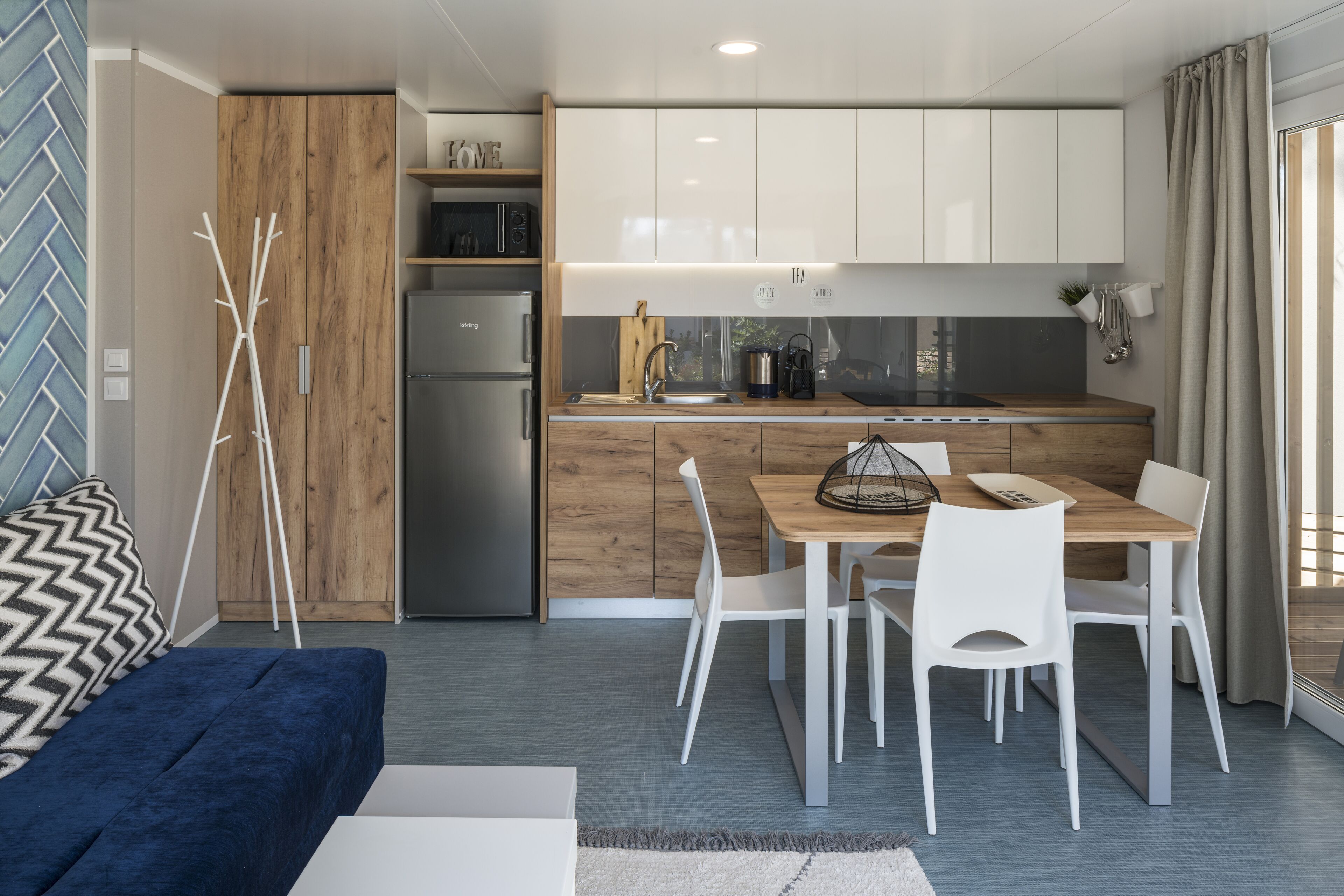 A modern kitchen with white cabinets, a wooden dining table, and a built-in oven.