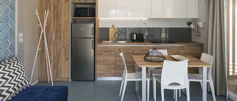 A modern kitchen with white cabinets, a wooden dining table, and a built-in oven.
