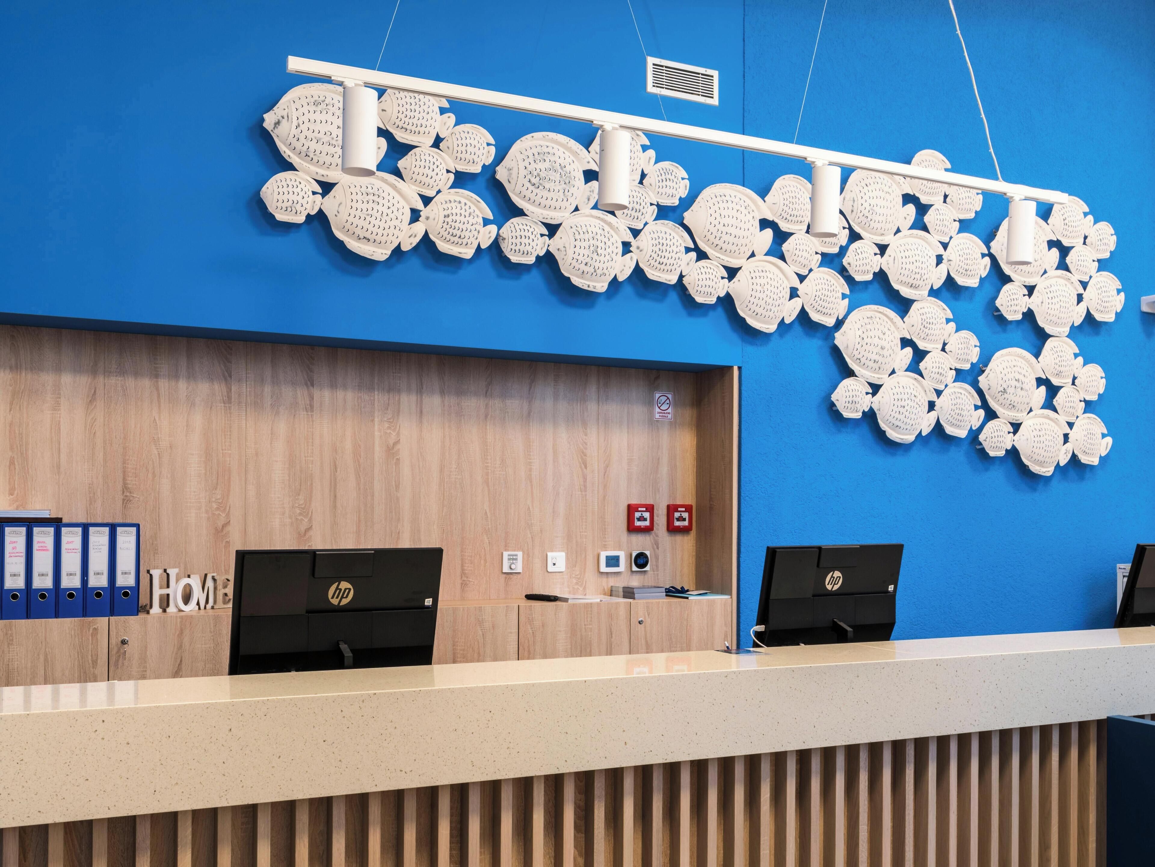 Un comptoir d’accueil avec un mur bleu, un panneau en bois et deux ordinateurs HP.