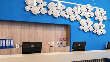 Un mostrador de recepción con pared azul, panel de madera y dos computadoras HP.