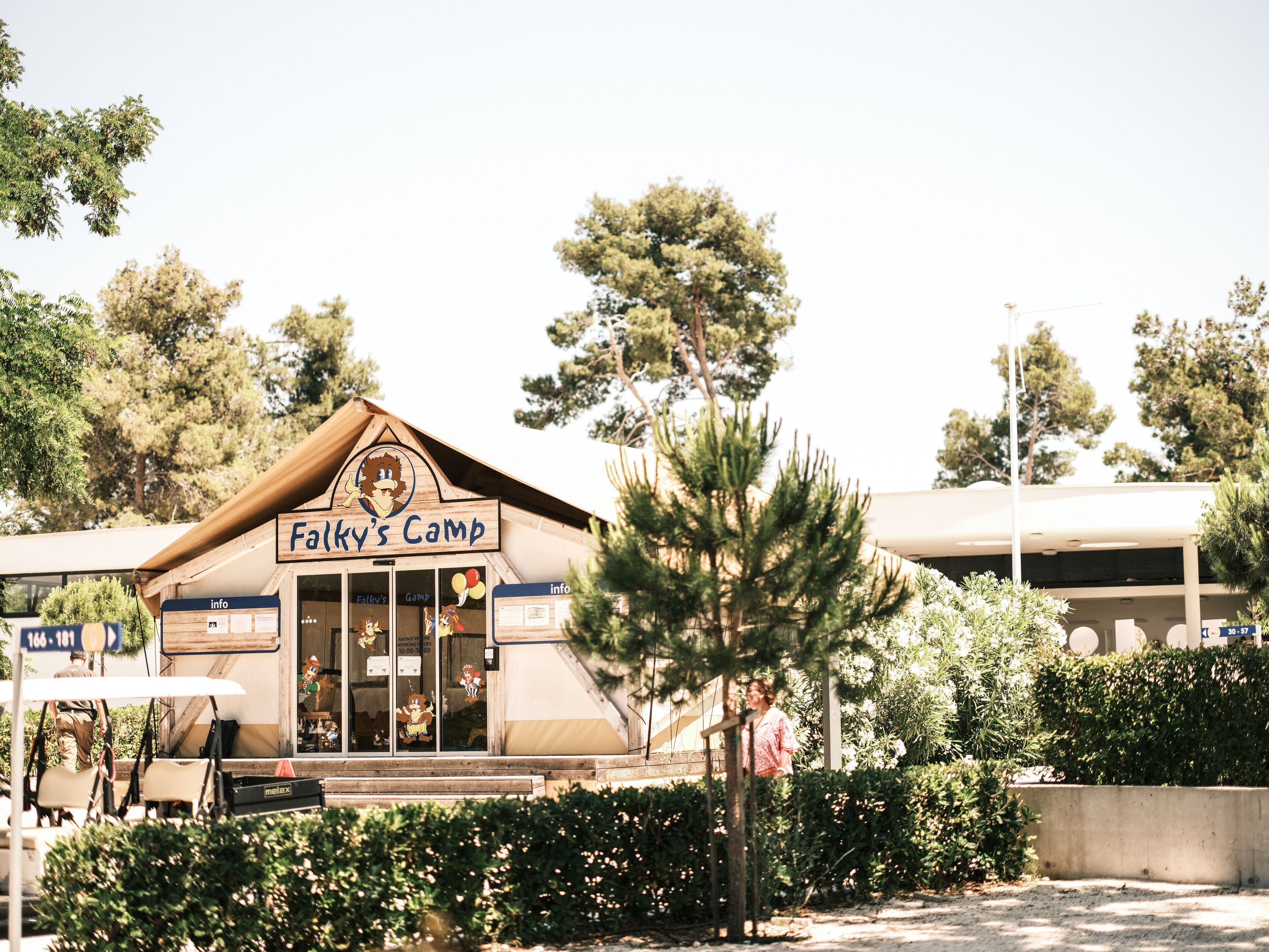 Un bâtiment portant l’inscription « Folky’s Camp », avec une enseigne, une petite entrée et un banc à l’extérieur.