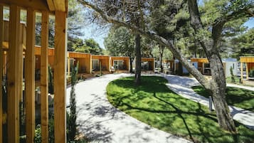A modern outdoor area with wooden structures, a paved walkway, and a well-maintained lawn.